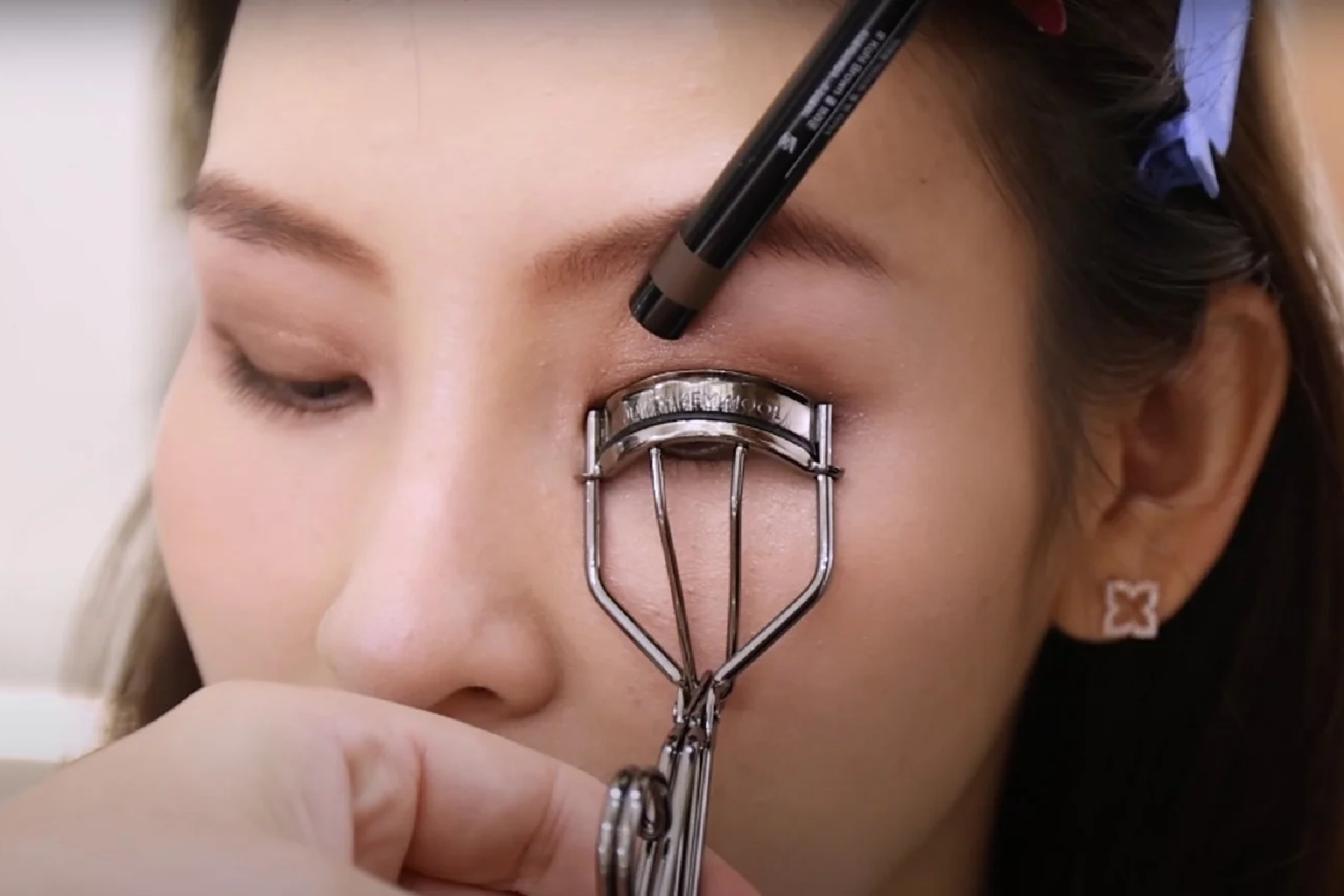 Home 9 Professional makeup artist applying eyelash curler to client